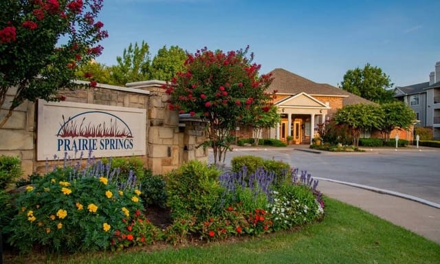 Entrance to Prairie Springs apartment community with landscaped entry sign.