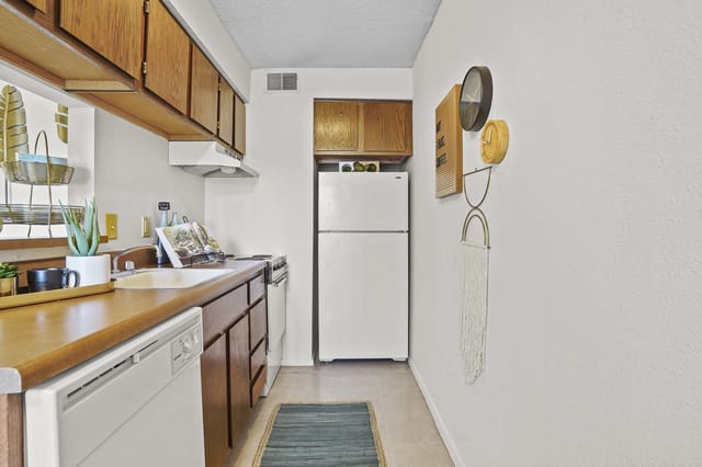 Kitchen with wooden cabinets, white appliances, and a sink.