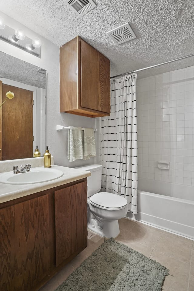 Bathroom with vanity, toilet, and bathtub with shower curtain.