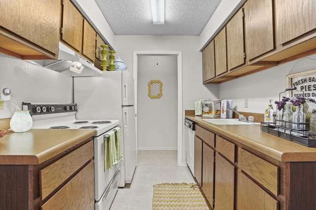 Kitchen with wood cabinets, white appliances, and light-colored countertops.