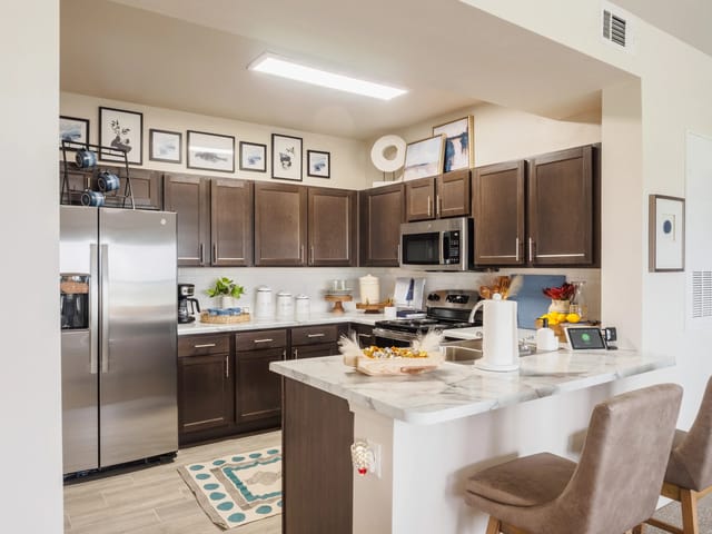Modern kitchen with dark wood cabinets, stainless steel appliances, and a marble island.