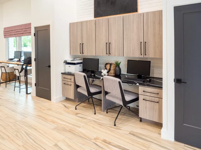 Interior of a community computer desk area with two workstations and wooden cabinets.