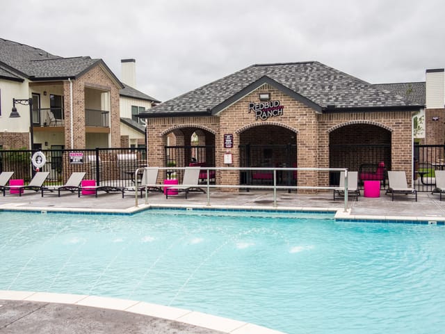 Outdoor apartment community pool with lounge chairs and a brick cabana.
