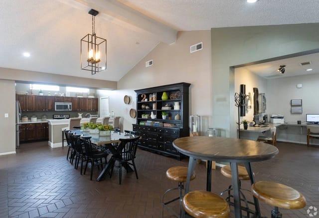 Open interior community lounge with a kitchen, dining table, and shelving unit.