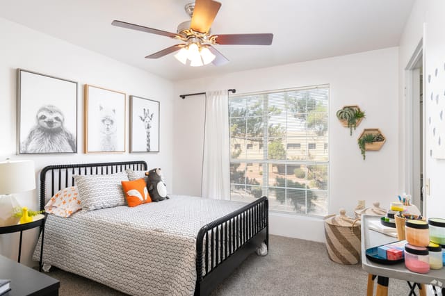 Bedroom with a queen-size bed, sloth and llama art, and a large window.