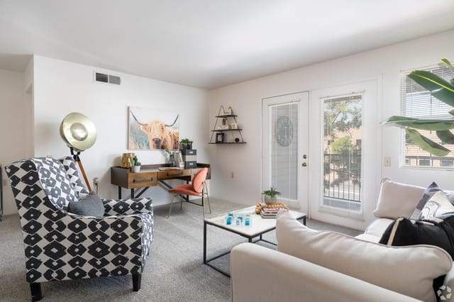 Living room with a decorative chair, a desk with a highland cow painting, and a sofa.