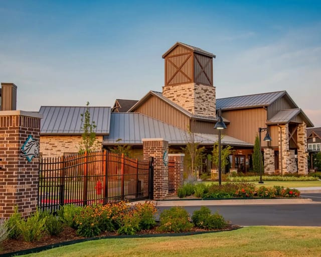Exterior view of a gated apartment community entrance with brick columns, stone accents, and landscaped grounds.