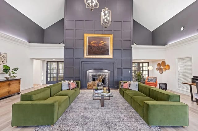 Lobby lounge with a dark paneled accent wall, a central fireplace, and olive-green sofas.
