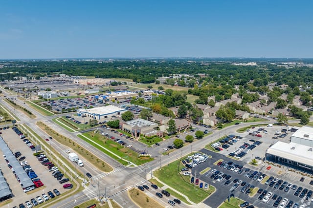 Aerial view of a large apartment community with nearby shopping centers and streets.