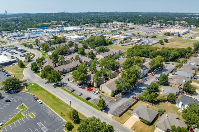 An aerial view of a multifamily apartment community with buildings, trees, and parking lots.