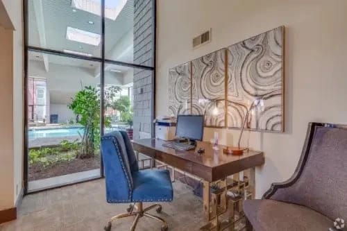 Leasing office with desk and blue chair, large glass window overlooking the outdoor pool.