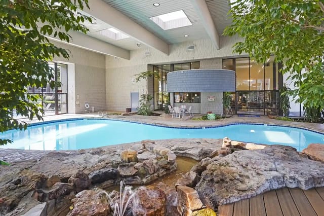 Indoor pool in an apartment community with rock features and seating.