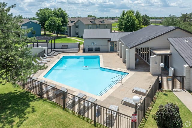 Aerial view of a community pool with lounge chairs and adjacent buildings.