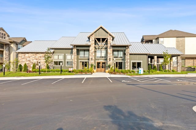 Exterior view of a modern apartment building with landscaping and parking spaces.