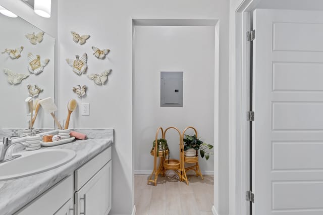 Bathroom vanity with marble countertop and decorative butterfly wall art.