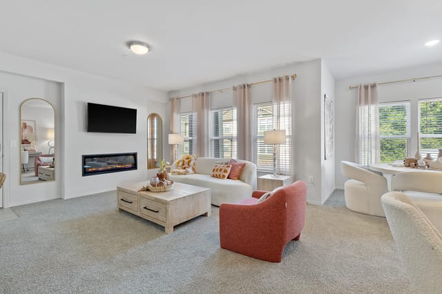 Modern living room with a fireplace, TV, sofa, and accent chair.