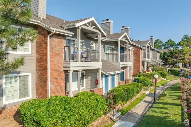 Exterior view of townhouse-style apartment buildings with balconies and landscaped walkways.
