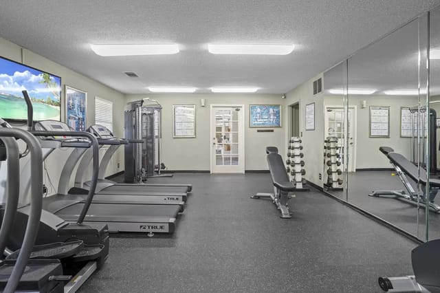 Interior view of a property gym with treadmills, weights, and a mirrored wall.