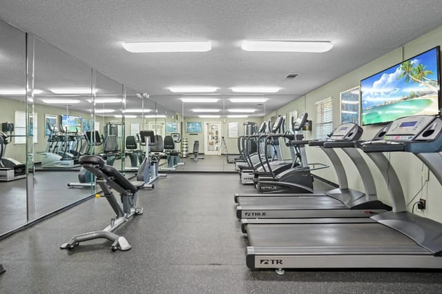 Indoor fitness center with treadmills, ellipticals, and mirrors.