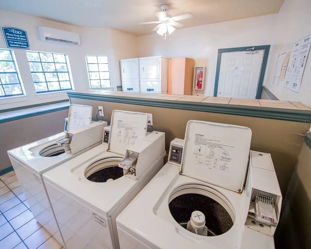 Community laundry room with several front-loading washing machines and dryers.