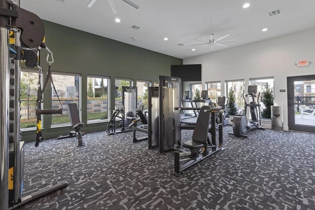 Modern apartment fitness center with cardio machines and weight/strength machines.