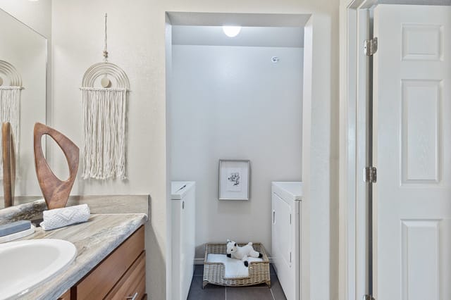 Bathroom vanity with a washer and dryer in a nearby closet.