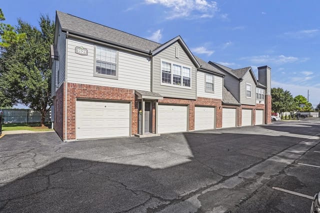 Exterior view of a multi-family building with a row of garage doors.