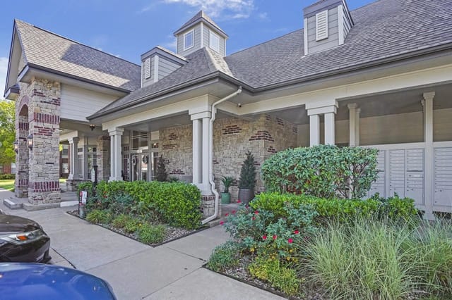 Exterior entrance of the apartment community with stone façade, columns, and landscaped plants.
