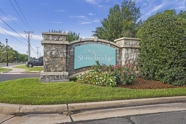 Stone entrance sign for Villages of Stonebridge with stone pillars and flowering plants.