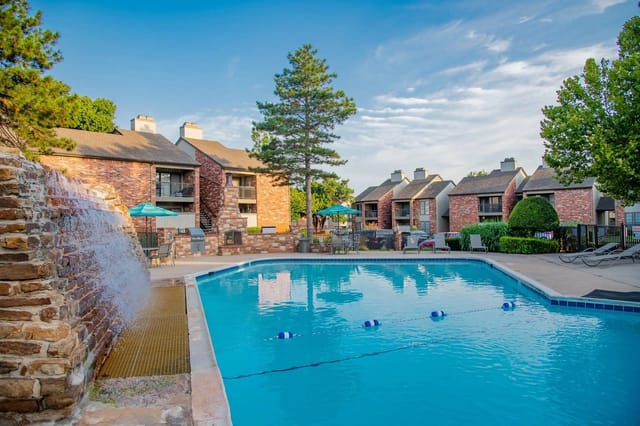 Outdoor pool area with lounge chairs and umbrellas at an apartment community.