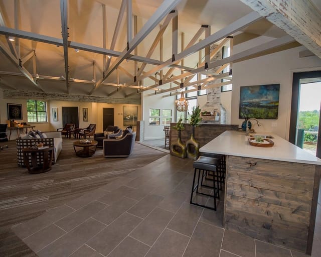Open community lounge with seating area, kitchen island, and exposed beams.