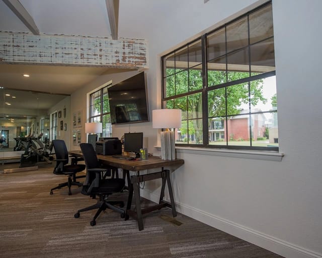 Interior of a modern community workspace with desks, chairs, and large windows.