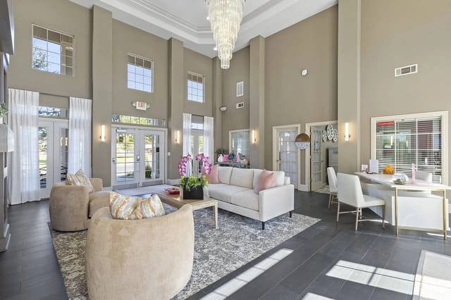 Bright lobby with high ceilings, large windows, chandelier, and seating.
