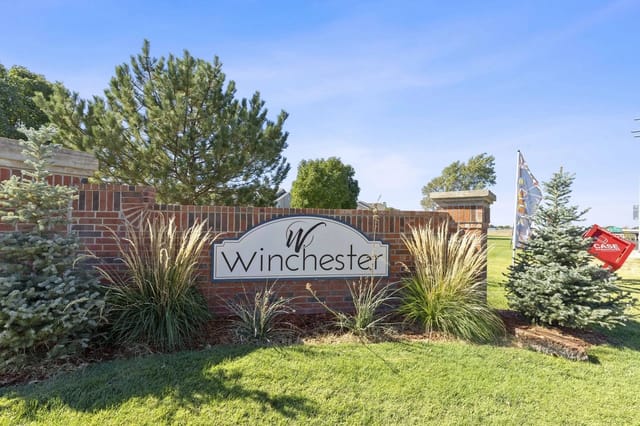 Brick entrance sign for Winchester community with shrubs and grasses.