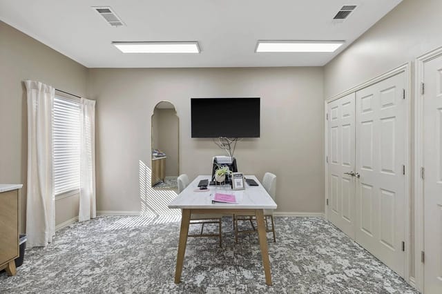 Leasing office/lounge with a table, chairs, and a wall-mounted TV.