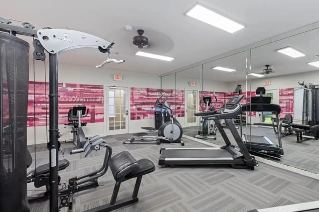 Indoor fitness center with treadmills, ellipticals, weight machines, and mirrors.