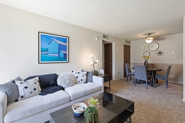 Living room in a modern apartment with a white sofa and dining area.