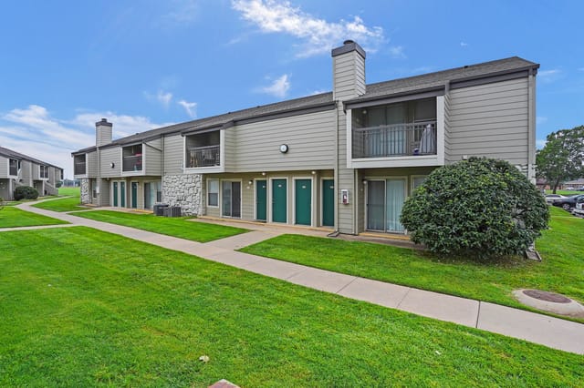 Exterior of apartment buildings with green lawns and walkways.