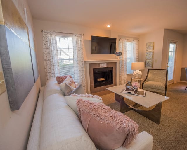 A living room with a pink couch and a fireplace.