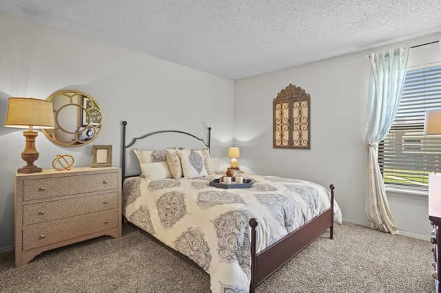 Cozy bedroom with a bed, lamp, and dresser.