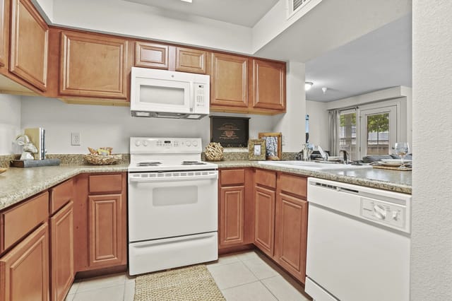 A kitchen with brown cabinets and white appliances.