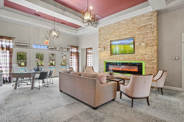 Spacious lounge area with fireplace, seating, and view of the pool.