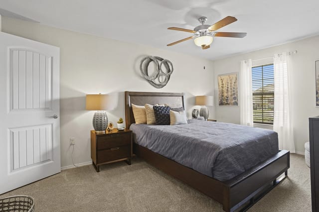 A bedroom with a bed, nightstand, and a ceiling fan.