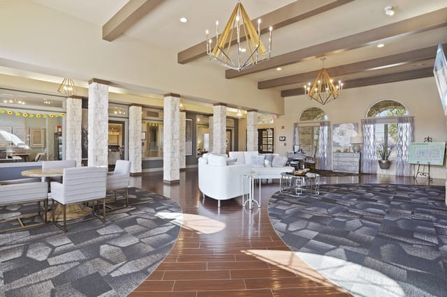 Spacious, modern community lounge with white sofas, contemporary light fixtures, and stone-clad columns.