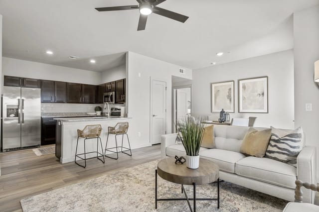 Open-concept living area with kitchen island, bar stools, and stainless steel appliances.