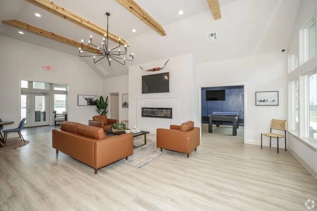 Bright clubhouse-style lounge with leather sofas, a fireplace, and large windows.