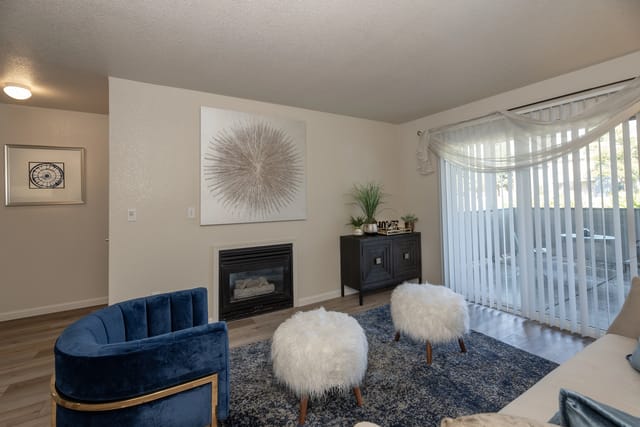 Living room with fireplace, blue armchair, and two white ottomans.