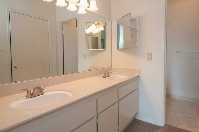 Double-sink bathroom vanity with large mirrors and warm lighting.