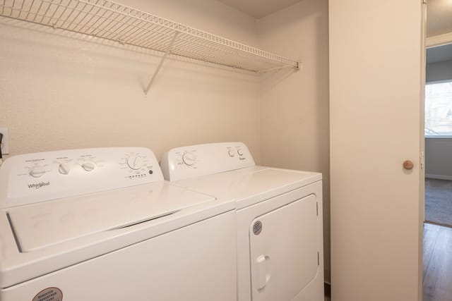 Laundry closet with a side-by-side washer and dryer and a wire shelf above.