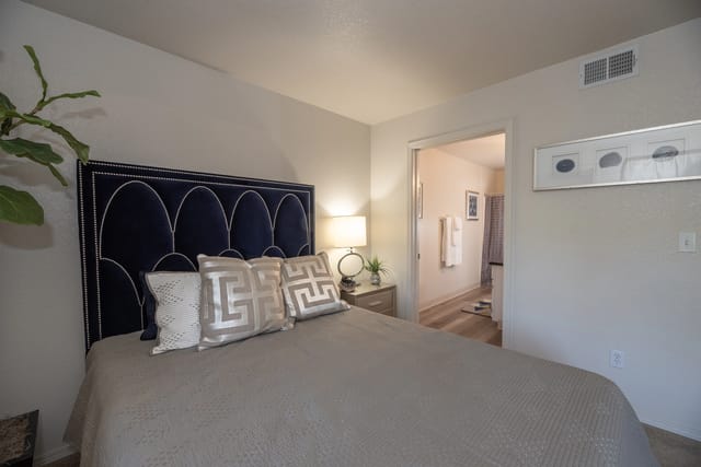 Bedroom with a navy blue headboard and beige bedding.